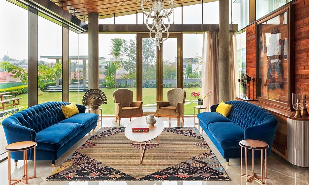 Luxury living room with blue velvet sofas and garden view by Curated Comfort interior studio Lucknow