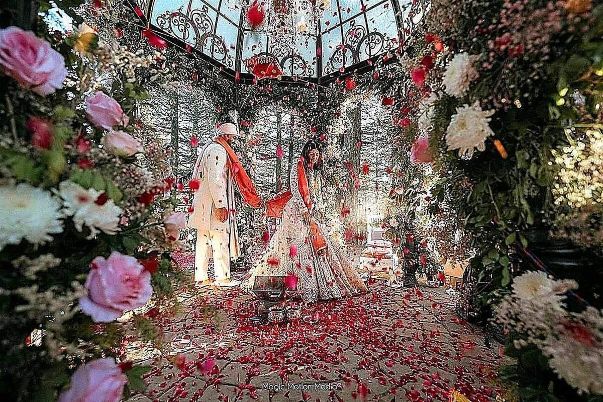Bride and groom in floral glass mandap decor by Nits Events, Lucknow wedding